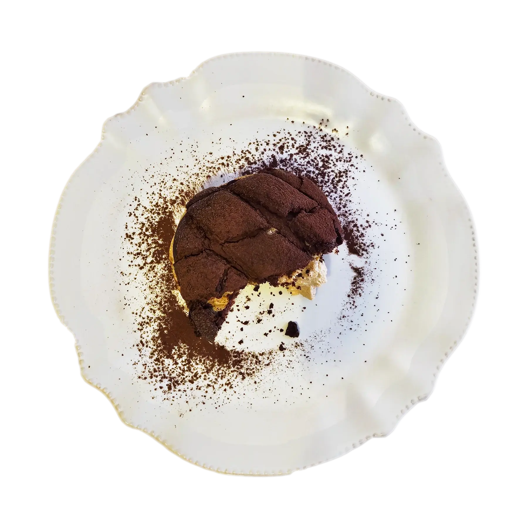 A tiramisu melonpan on a white plate with a bite taken out, showing the filling