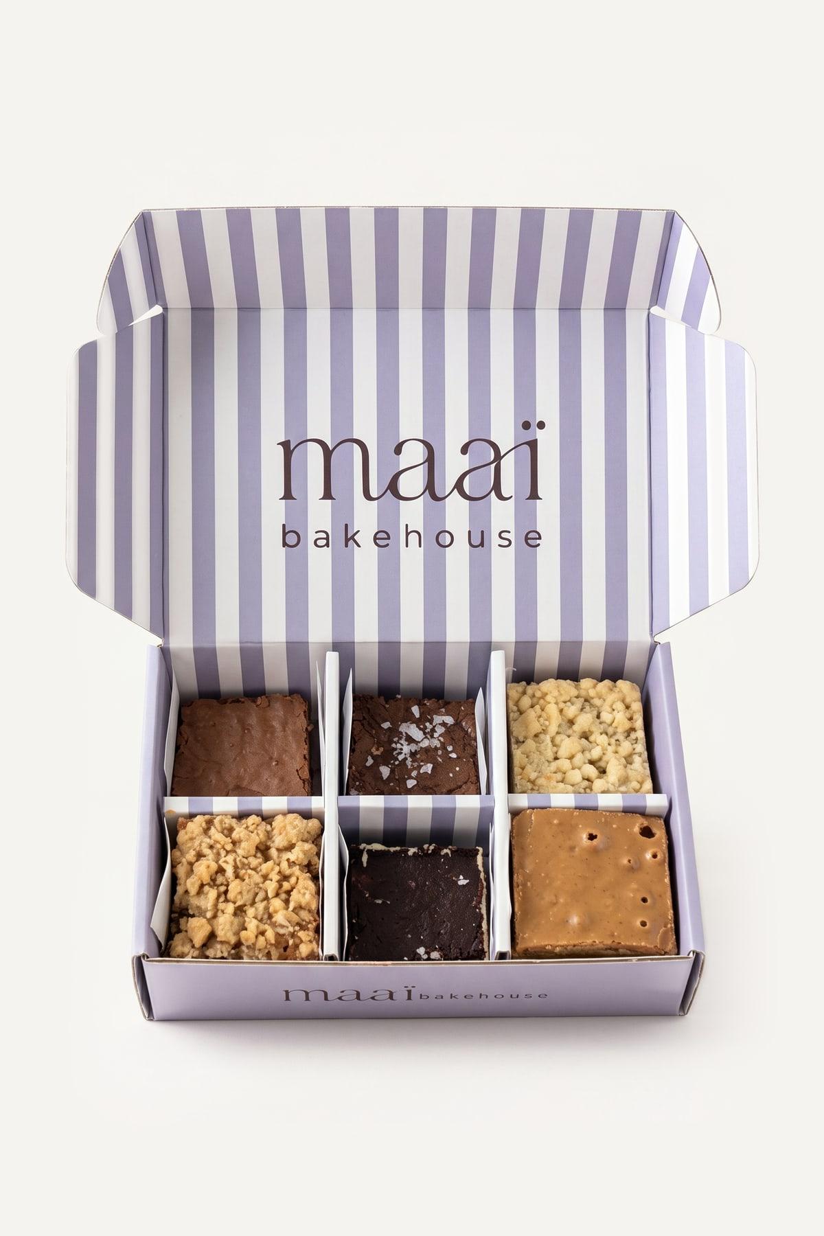 The open box of six, its striped lid up, with three brownies and three blondies in the compartments