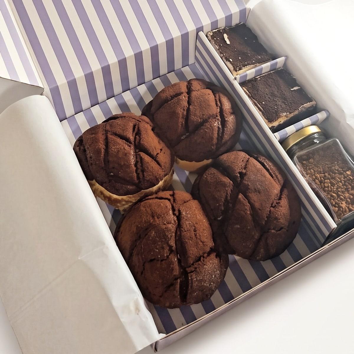 The maaï box open, with four tiramisu melonpan, two tiramisu brownies and a jar of coffee in the striped box