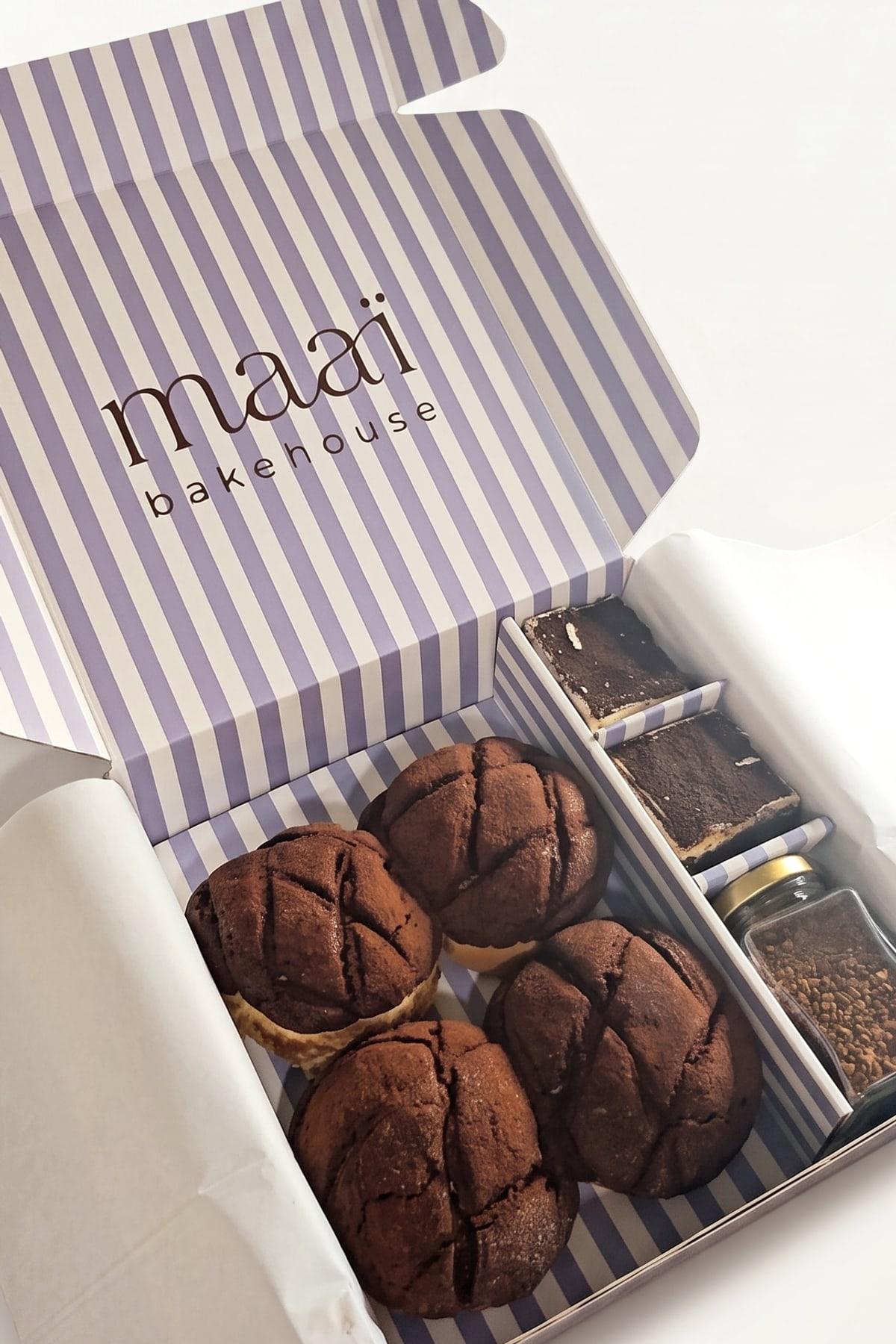 The maaï box open, with four tiramisu melonpan, two tiramisu brownies and a jar of coffee in the striped box