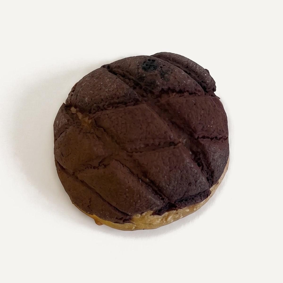 A tiramisu melonpan from above: a cocoa crust scored in diamonds over a golden bun