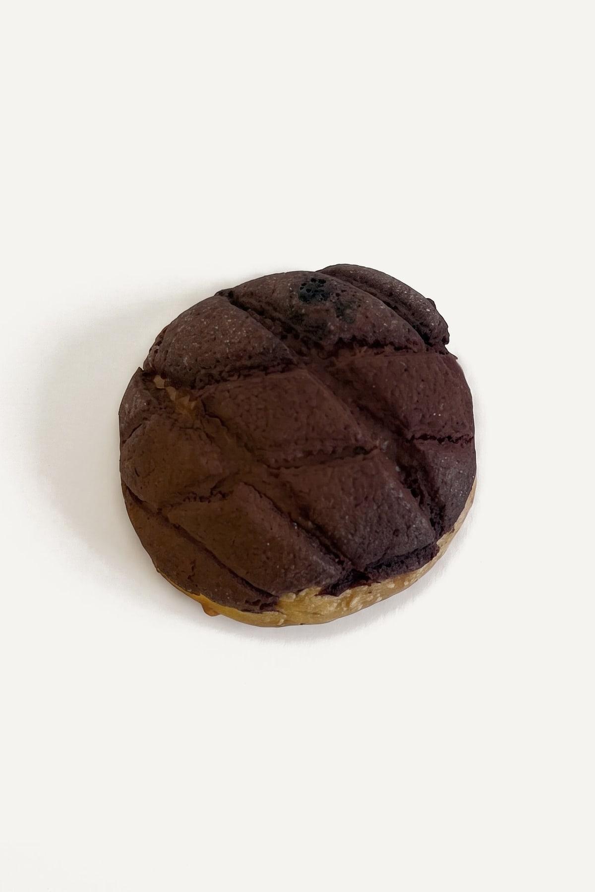 A tiramisu melonpan from above: a cocoa crust scored in diamonds over a golden bun