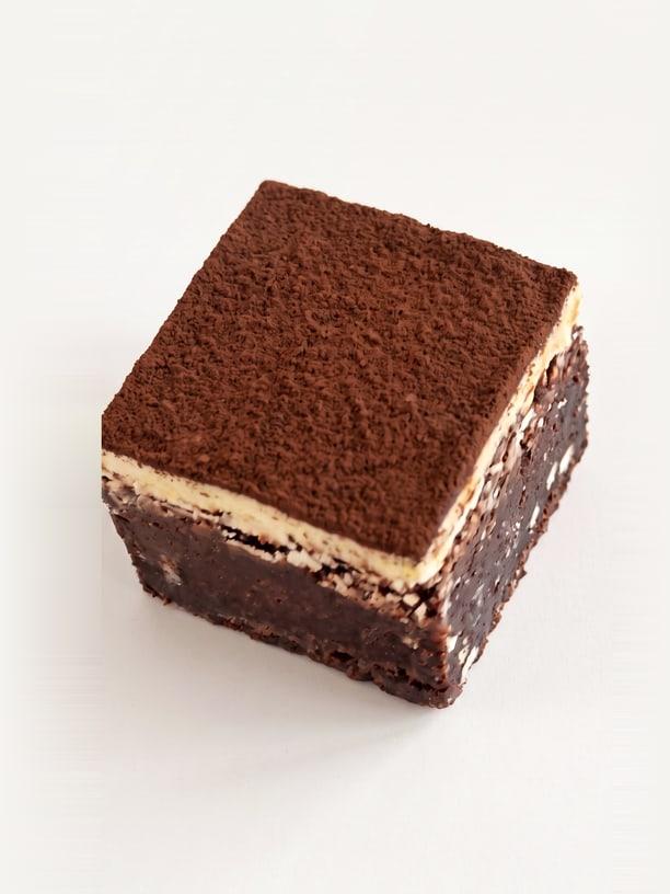 A tiramisu brownie with a cocoa-dusted top over a thin pale layer
