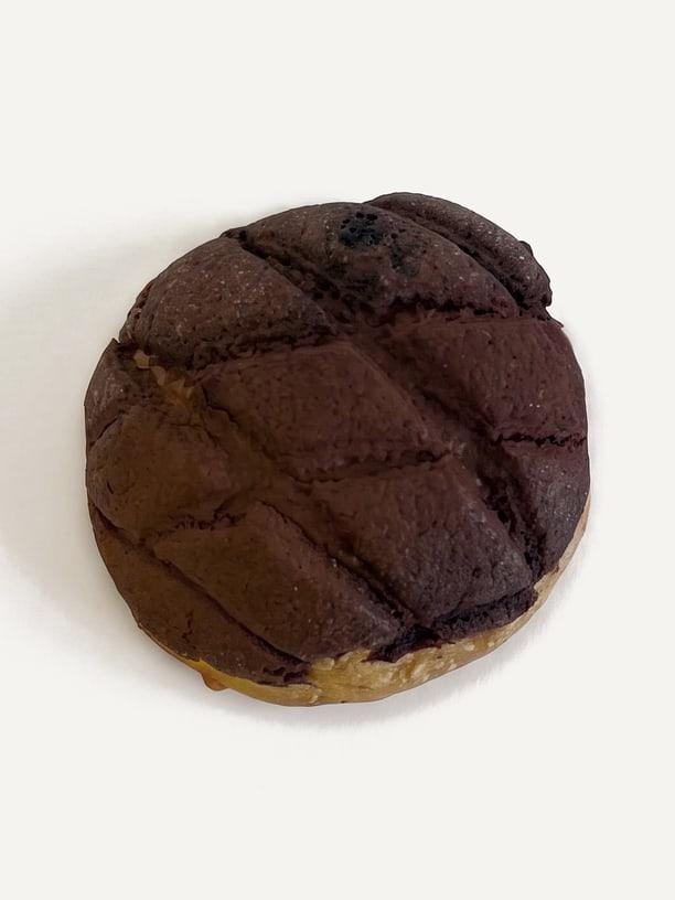 A tiramisu melonpan from above: a cocoa crust scored in diamonds over a golden bun