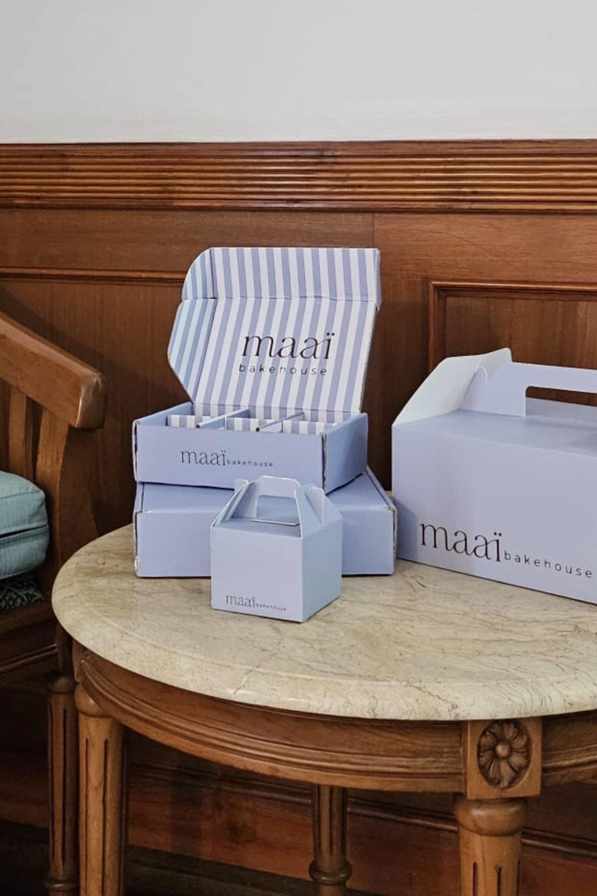 Striped maaï bakehouse boxes stacked on a marble table